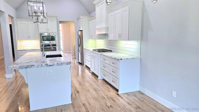 kitchen featuring backsplash, stainless steel appliances, vaulted ceiling, and light hardwood / wood-style floors