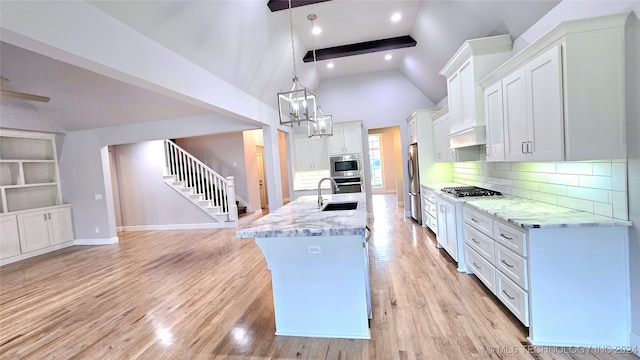 kitchen featuring pendant lighting, beamed ceiling, white cabinets, light hardwood / wood-style flooring, and decorative backsplash