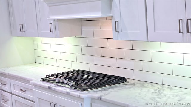 kitchen with decorative backsplash, white cabinets, stainless steel gas cooktop, and premium range hood