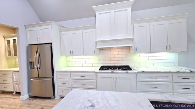 kitchen featuring stainless steel appliances, white cabinets, light stone countertops, tasteful backsplash, and light hardwood / wood-style flooring