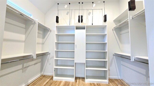 walk in closet with light hardwood / wood-style flooring and vaulted ceiling