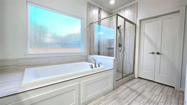 bathroom with tile patterned floors, crown molding, and separate shower and tub