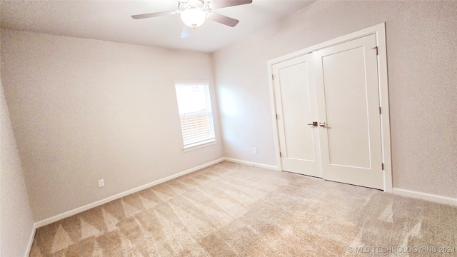 unfurnished bedroom featuring ceiling fan, light carpet, and a closet