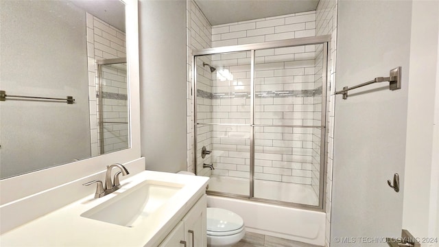 full bathroom featuring shower / bath combination with glass door, toilet, and vanity