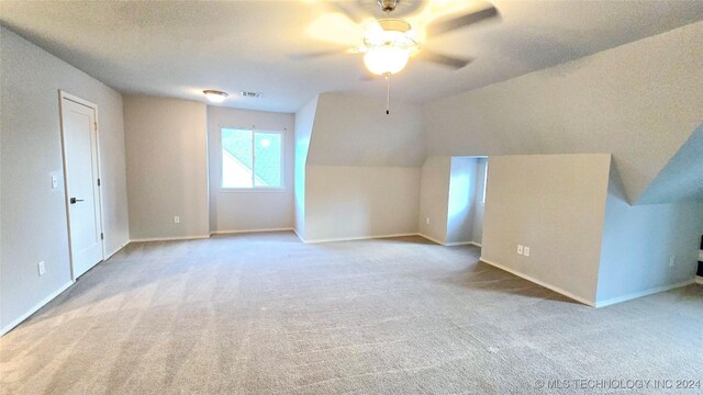 additional living space with light carpet, a textured ceiling, lofted ceiling, and ceiling fan