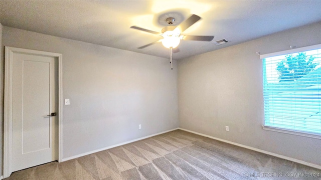 spare room with ceiling fan and light colored carpet