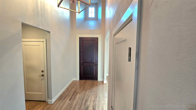 corridor with a towering ceiling and light hardwood / wood-style floors