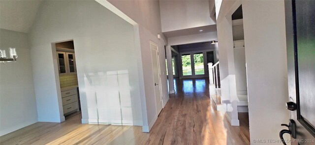 corridor featuring light hardwood / wood-style flooring and high vaulted ceiling