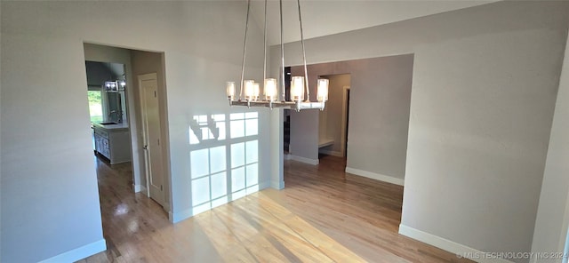 unfurnished dining area with hardwood / wood-style floors and an inviting chandelier