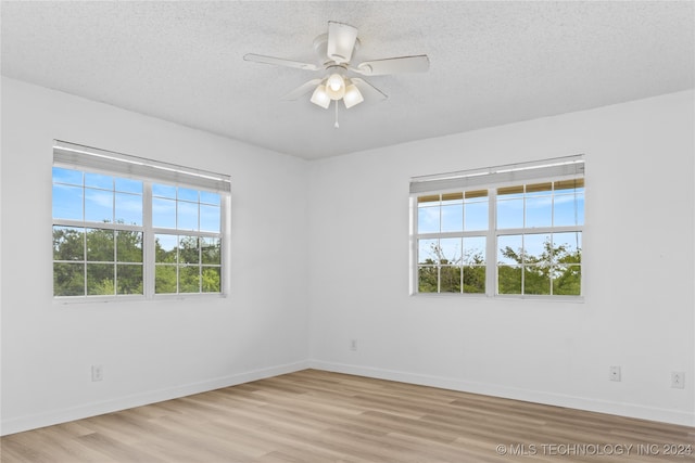 unfurnished room featuring ceiling fan, light wood-type flooring, a textured ceiling, and a wealth of natural light