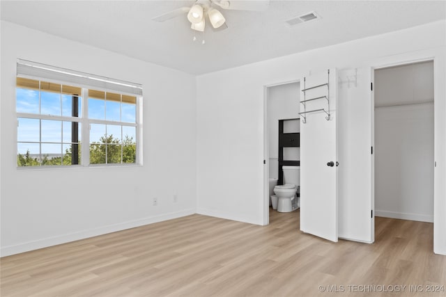 unfurnished bedroom featuring a walk in closet, light wood-type flooring, a closet, and connected bathroom