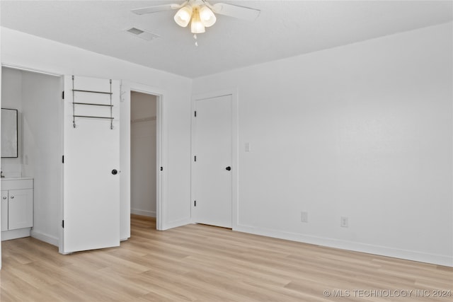 unfurnished bedroom featuring light wood-type flooring, a closet, ceiling fan, and ensuite bathroom