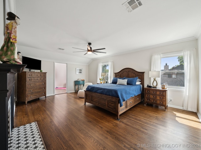 bedroom with crown molding, a fireplace, visible vents, and dark wood-style flooring