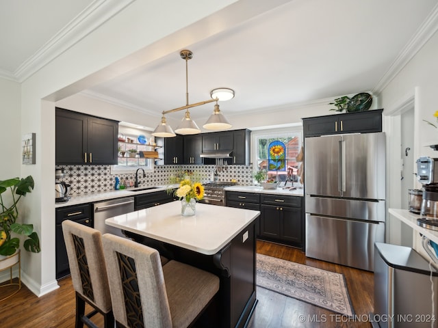 kitchen featuring a sink, light countertops, appliances with stainless steel finishes, a center island, and decorative light fixtures