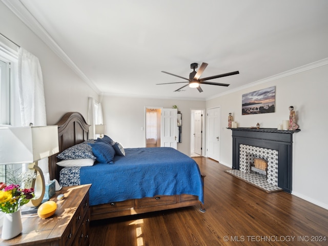 bedroom featuring a tiled fireplace, dark wood-type flooring, ornamental molding, ceiling fan, and baseboards