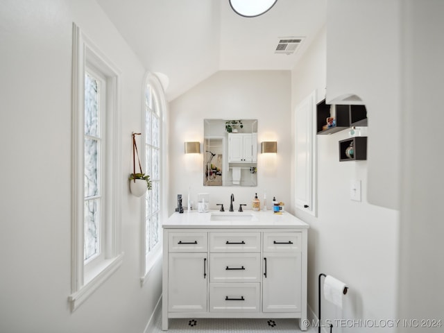 bathroom featuring lofted ceiling, a healthy amount of sunlight, visible vents, and vanity