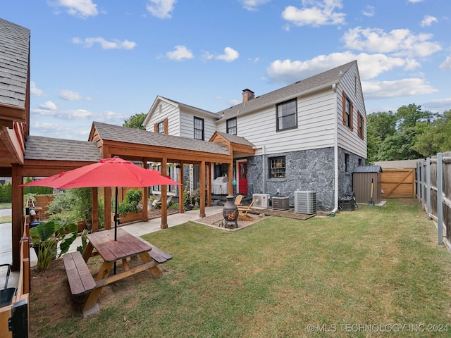 rear view of property with a patio, an outdoor fire pit, a lawn, and central air condition unit