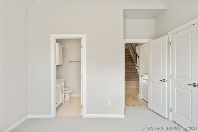 unfurnished bedroom featuring light wood-type flooring, a closet, and connected bathroom