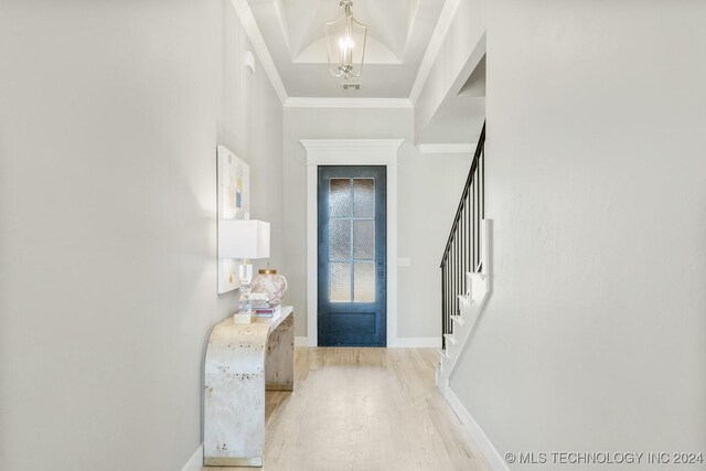 foyer featuring baseboards, a notable chandelier, wood finished floors, stairway, and crown molding