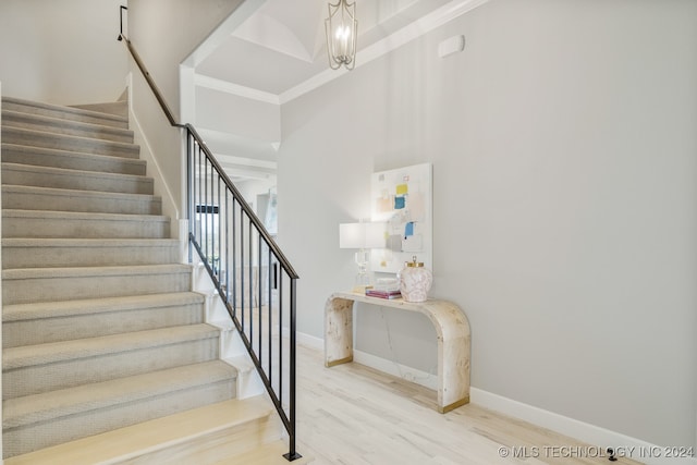 stairway featuring a towering ceiling, ornamental molding, and hardwood / wood-style flooring