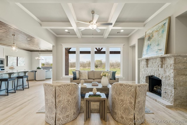 living area with a stone fireplace, ceiling fan with notable chandelier, light wood-style floors, coffered ceiling, and beam ceiling