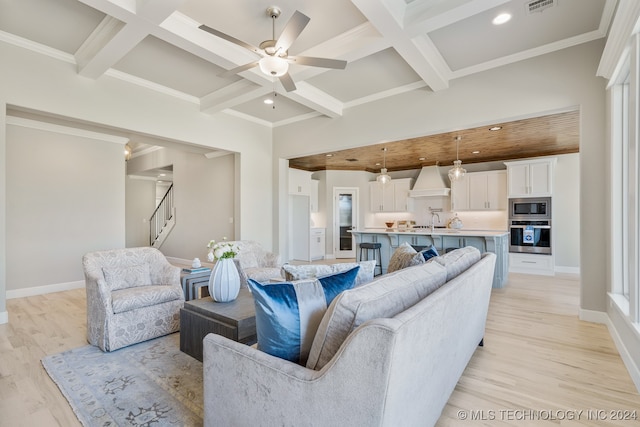 living room featuring coffered ceiling, light wood-type flooring, ceiling fan, sink, and beamed ceiling