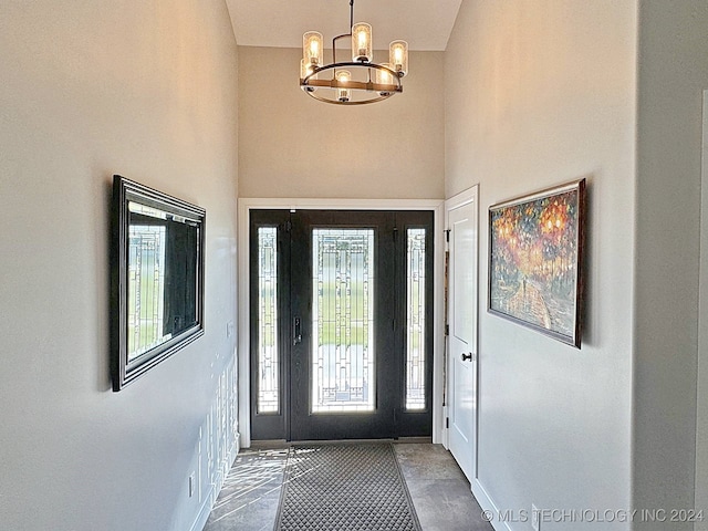 entrance foyer with tile patterned floors, a chandelier, and a towering ceiling