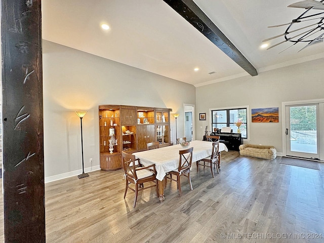 dining space with beam ceiling, a high ceiling, a chandelier, and light hardwood / wood-style floors