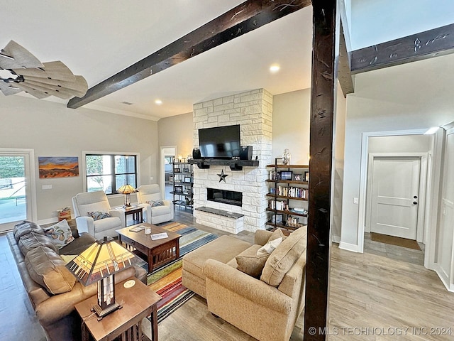 living room featuring beam ceiling, a fireplace, and light hardwood / wood-style floors