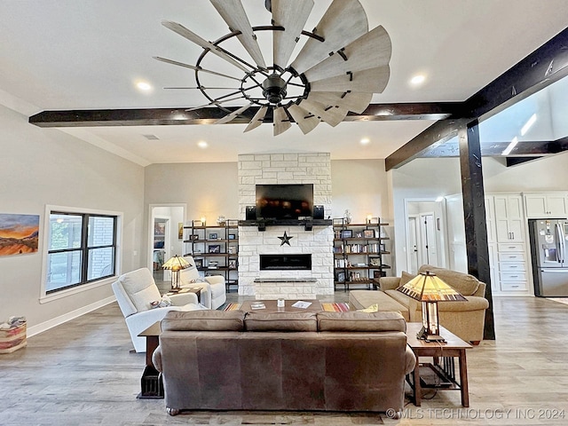 living room with beamed ceiling, a fireplace, and light hardwood / wood-style floors