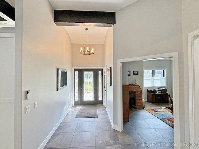 foyer with beam ceiling, light tile patterned flooring, an inviting chandelier, and a high ceiling