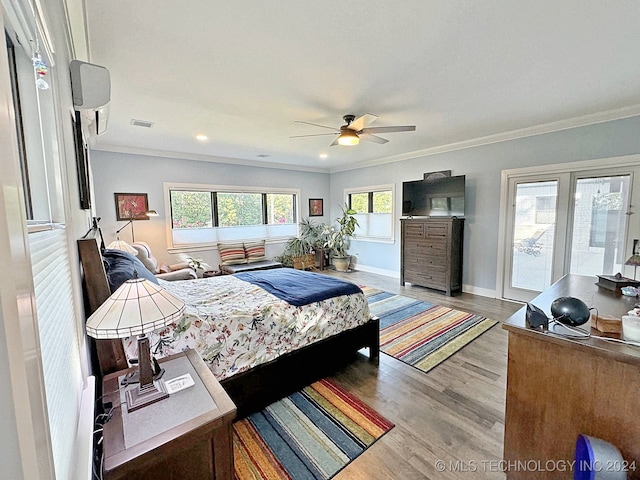 bedroom featuring crown molding, hardwood / wood-style floors, ceiling fan, and multiple windows