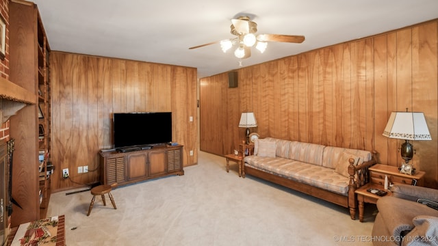 living room featuring light colored carpet, wood walls, and ceiling fan