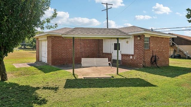 back of property with a patio, a garage, and a lawn