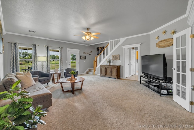 living room featuring ceiling fan, a textured ceiling, crown molding, and light colored carpet