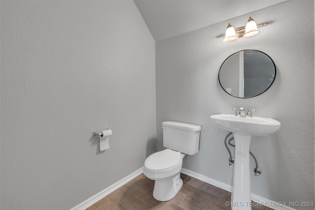 bathroom featuring hardwood / wood-style floors, vaulted ceiling, and toilet