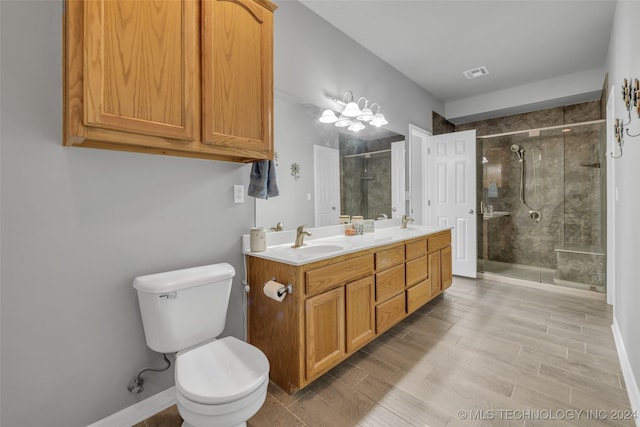 bathroom with dual bowl vanity, toilet, and a shower with door