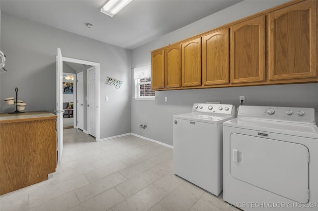 laundry room with washing machine and clothes dryer, cabinets, and light tile patterned floors