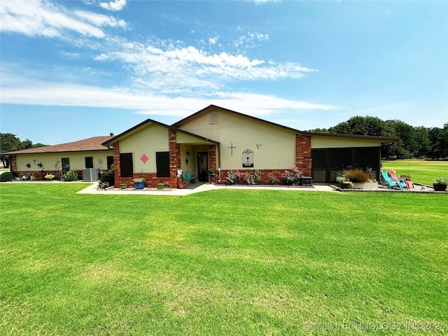 view of front of home with central AC unit and a front yard