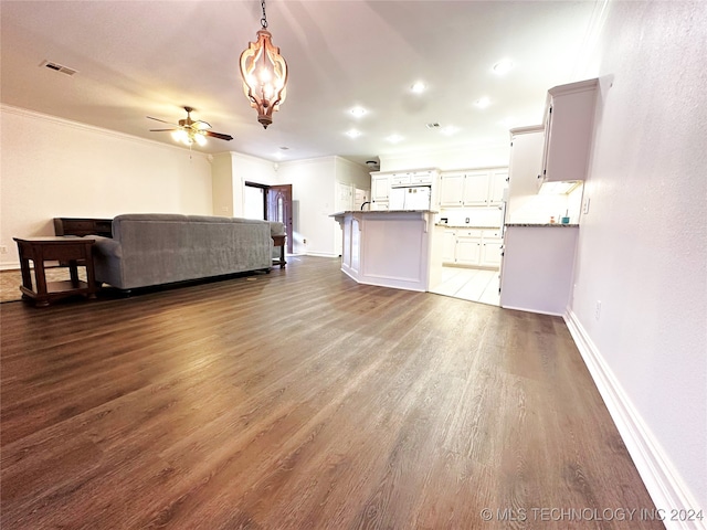 interior space featuring dark wood-type flooring, white cabinetry, ornamental molding, pendant lighting, and ceiling fan