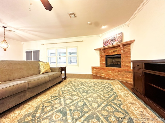 living room with a brick fireplace, crown molding, wood-type flooring, and ceiling fan