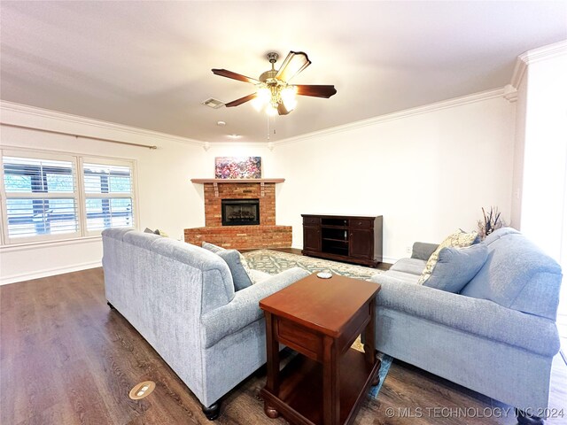 living room with dark hardwood / wood-style floors, ceiling fan, ornamental molding, and a fireplace