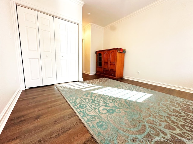 unfurnished bedroom featuring dark hardwood / wood-style flooring, ornamental molding, and a closet