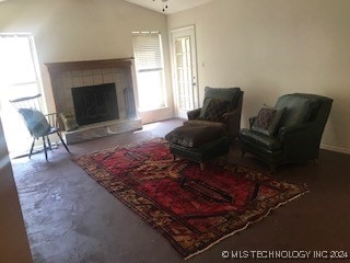 living room featuring ceiling fan, a fireplace, and lofted ceiling