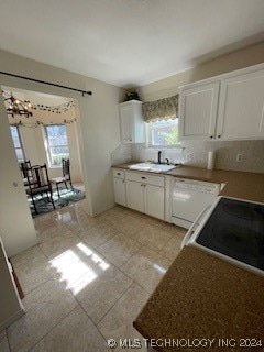 kitchen featuring decorative backsplash, sink, an inviting chandelier, white cabinetry, and light tile patterned flooring