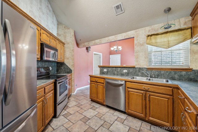 kitchen with lofted ceiling, a textured ceiling, stainless steel appliances, sink, and decorative light fixtures