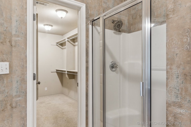 bathroom featuring a textured ceiling and a shower with shower door