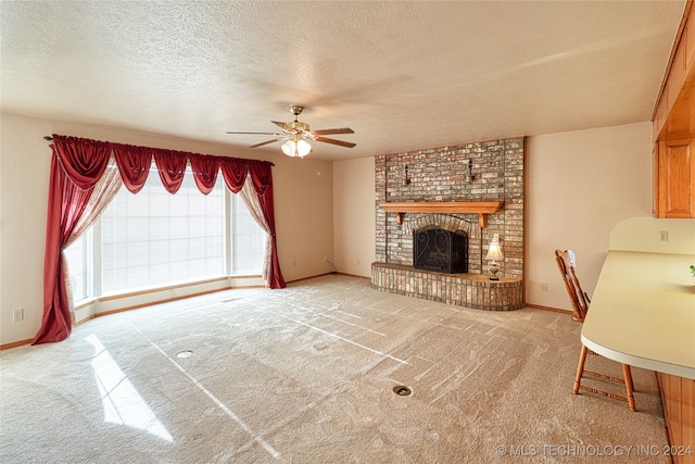 living room with a textured ceiling, a fireplace, ceiling fan, and light colored carpet