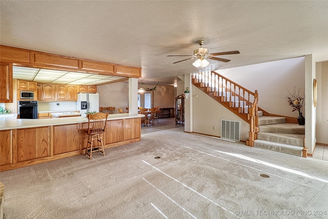 kitchen with light colored carpet, kitchen peninsula, black oven, white refrigerator with ice dispenser, and stainless steel microwave