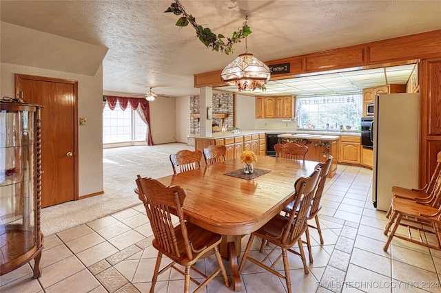 tiled dining area featuring a textured ceiling and ceiling fan with notable chandelier